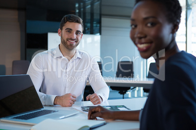 Portrait of smiling executives sitting at desk