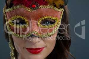 Woman wearing masquerade mask against black background