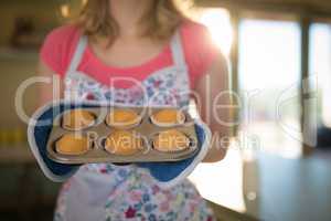 Woman holding tray of muffins in restaurant