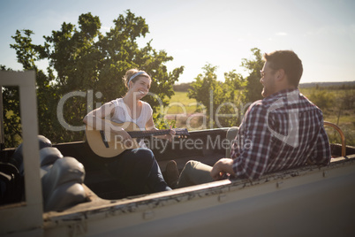 Woman playing guitar while man listening in a car