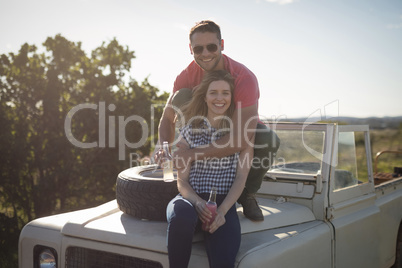 Couple having drinks on the bonnet of car