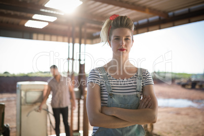 Woman standing with arms crossed at petrol pump station