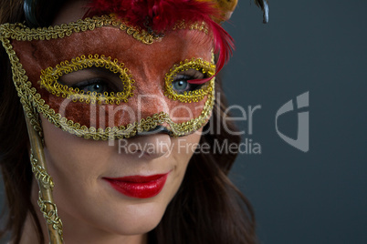 Woman wearing masquerade mask against grey background