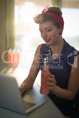 Woman using laptop while having drink in restaurant