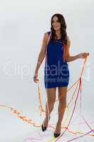 Woman wrapped in multi color streamers posing against white background