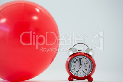 Red balloon and alarm clock on white background