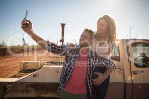 Couple taking selfie with mobile phone near a car
