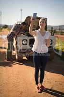 Woman taking selfie with mobile phone while man repairing a car