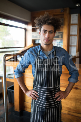 Confident waiter standing with hands on hip in bar