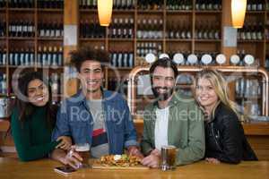 Group of friends having glass of beer and mexican food in bar