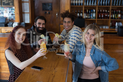 Friends having glass of drinks at counter in bar