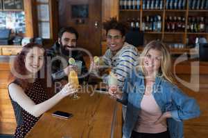 Friends having glass of drinks at counter in bar