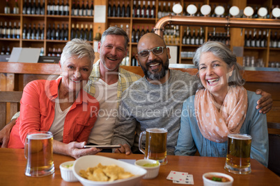 Happy friends sitting together at bar