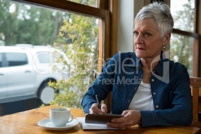 Senior woman writing in a diary