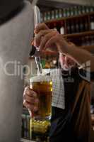 Brewer filling beer in beer glass from beer pump