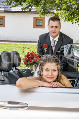 Bridal couple with wedding car