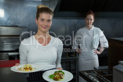 Female chefs holding food plates
