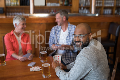 Happy friends playing cards while having glass of beer