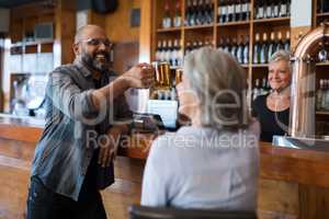 Friends toasting glass of beer at counter in bar
