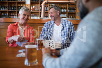 Happy friends playing cards while having glass of beer