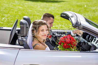 Bridal couple with wedding car