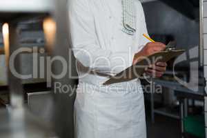 Male chef writing order on a clipboard