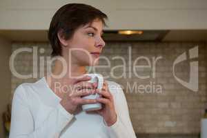 Thoughtful woman having cup of coffee in kitchen