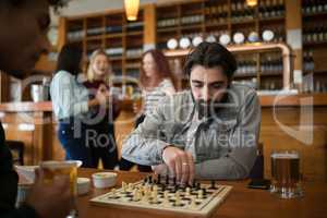 Two men playing chess while having glass of beer