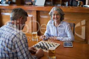 Friends playing chess while having glass of beer in bar