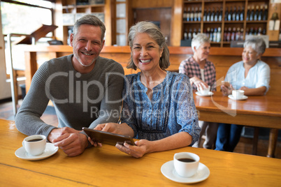 Smiling senior couple using digital tablet in restaurant