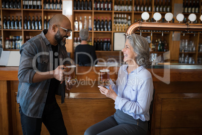 Two friends having glass of beer at counter in restaurant