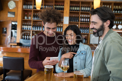 Friends looking their photos on mobile phone in bar