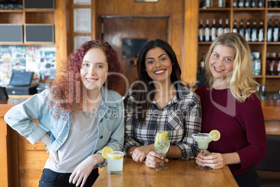 Happy female friends standing together in bar