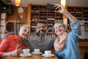 Friends taking selfie with mobile phone in bar