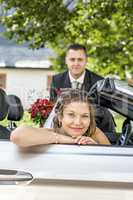 Bridal couple with wedding car