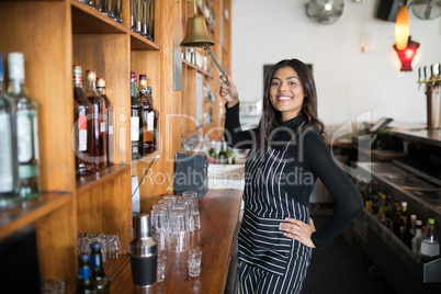 Smiling waitress ringing bell at counter