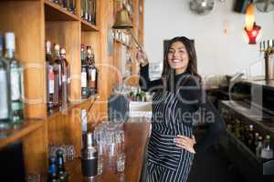 Smiling waitress ringing bell at counter