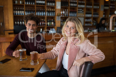 Happy couple having glass of beer in bar