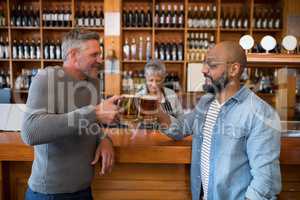 Friends toasting glass of beer at counter in restaurant