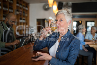 Senior woman having glass of wine at counter