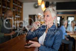 Senior woman having glass of wine at counter
