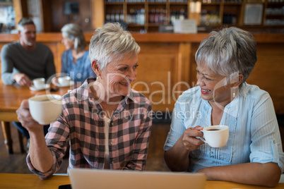 Smiling senior friends having cup of tea in restaurant