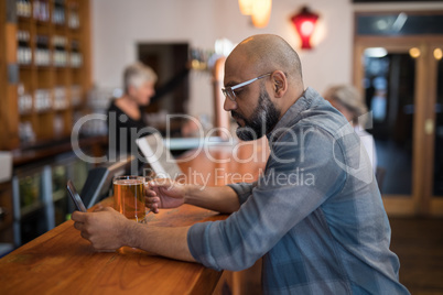 Man using mobile phone while having glass of beer