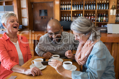 Friends looking their photos on mobile phone in bar