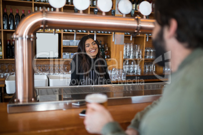 Smiling waitress talking to man at counter