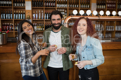 Smiling friends having tequila at counter in bar