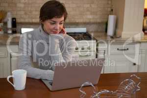 Woman using laptop in kitchen