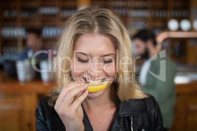Beautiful woman biting into lemon wedge after having tequila shot
