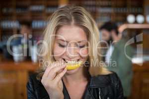 Beautiful woman biting into lemon wedge after having tequila shot