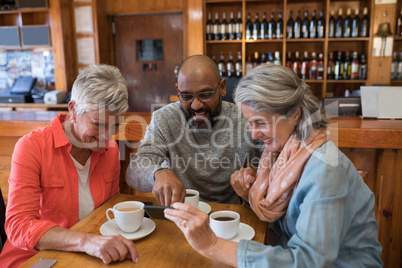 Friends looking their photos on mobile phone in bar